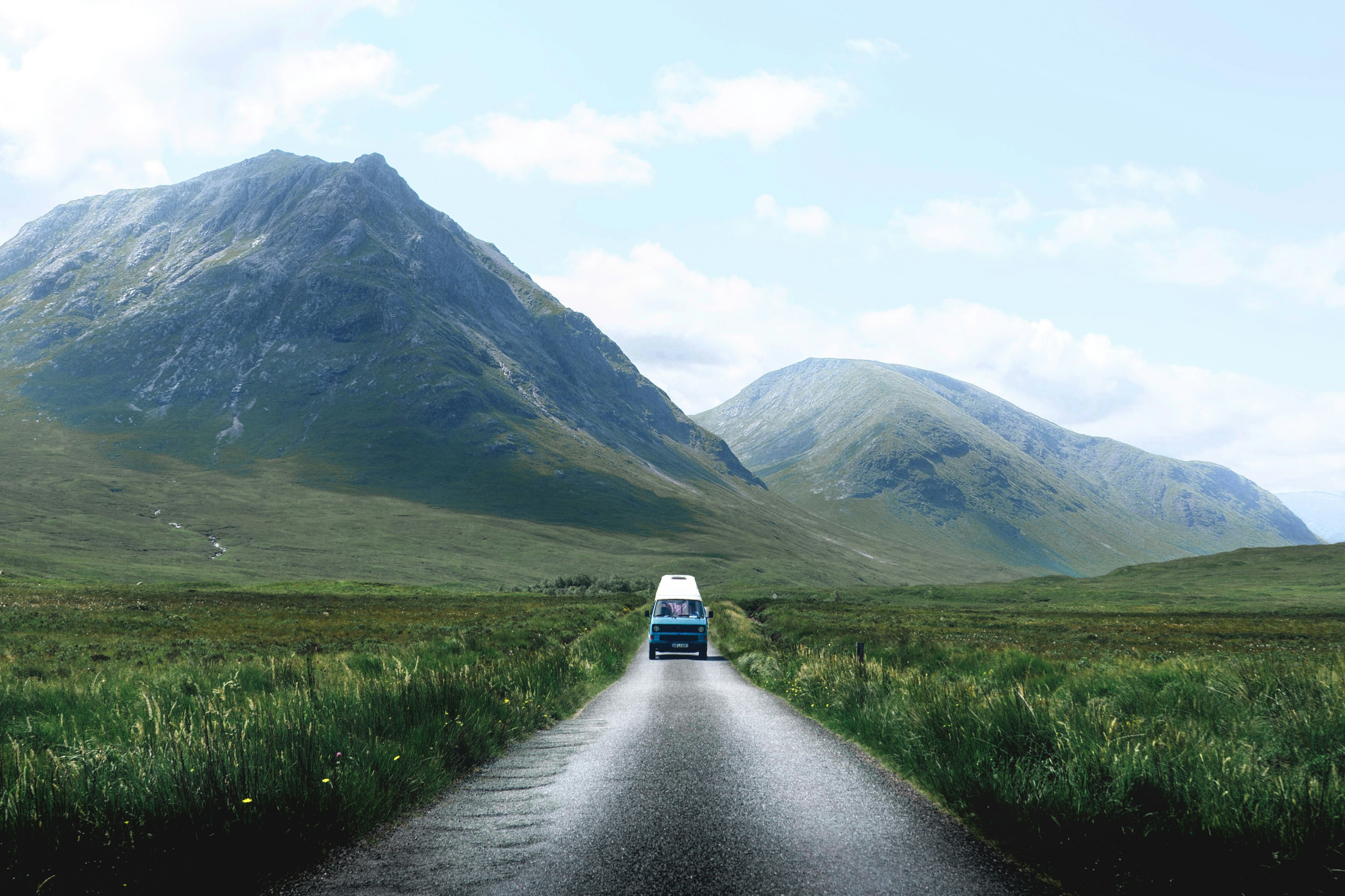 blue vehicle passing through grass field